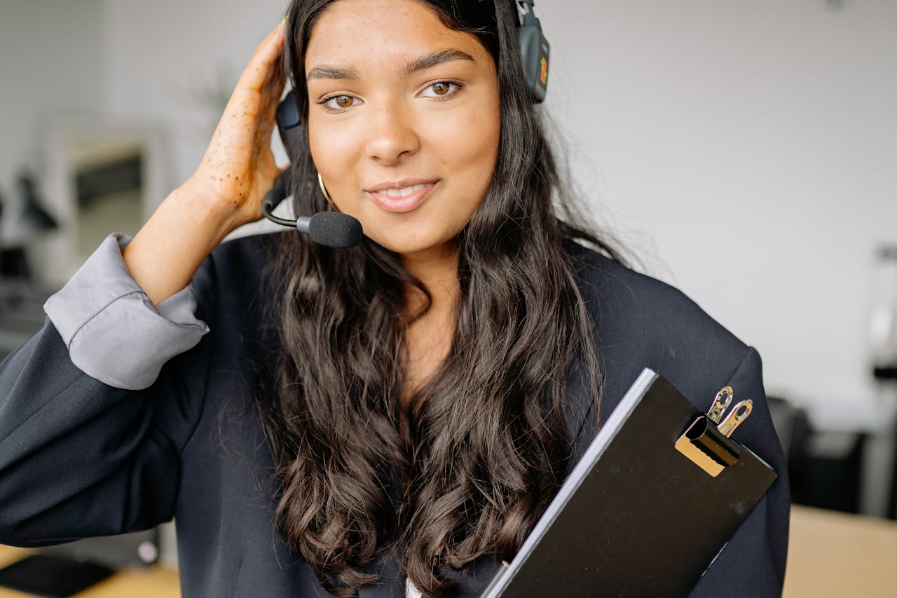 Smiling female call center representative with a headset in an office setting.